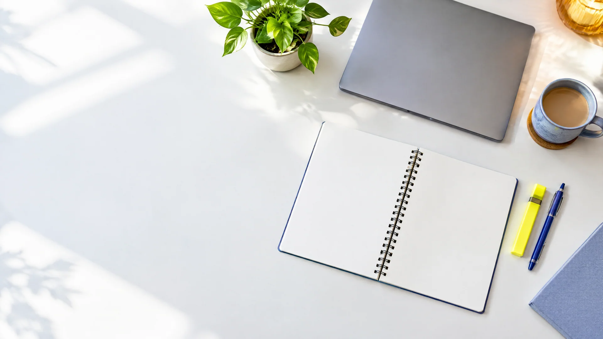 Desk with an open blank notebook, highlighter and pen